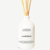 reed diffuser white opaque bottle with 5 sticks. on the bottle there is the logo, room essentials  and the word wonderland  Lusensa