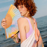 Young woman at the beach holding a hand fan with calm collor palette