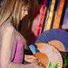 young woman holding two colorful hand fans