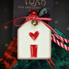 detail of a christmas ornament with a white house and a red heart