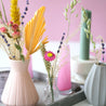 little white and glass vases with a selection of colorful dried flowers