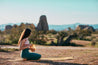 young woman in sportswear on a yoga mat outdoors on  rocky surroundings holding a stasher silicone bag 