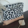 beach bag with cork and leopard patterned fabric on a dark brown surface with decorative eaves