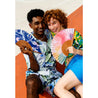 happy couple sitting wearing colorful clothes holding open fans looking at the camera 