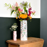 two paper vases with colorful flowers on a wooden old table