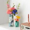 paper vases with fresh flowers on a white table by a radio