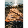 orange peshtemal towel with white stripes by the calm sea during the sunset