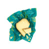 A piece of cheece on a blue green beeswax wrap 